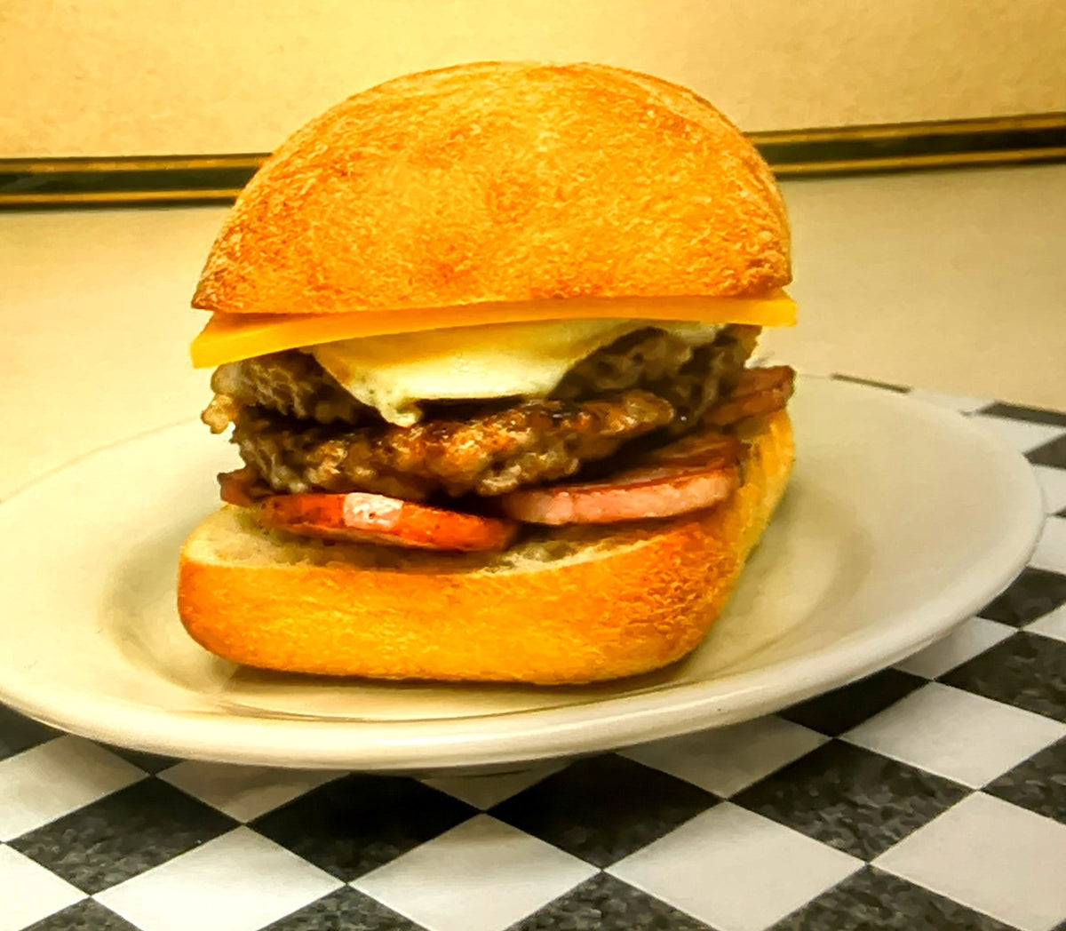 Breakfast bap with sausage patty, egg, cheese and rasher
