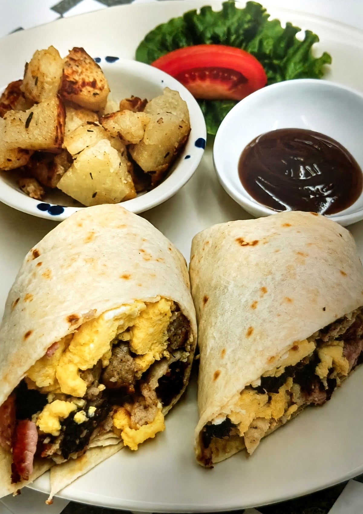 Breakfast burrito with egg and sausage, served with potatoes