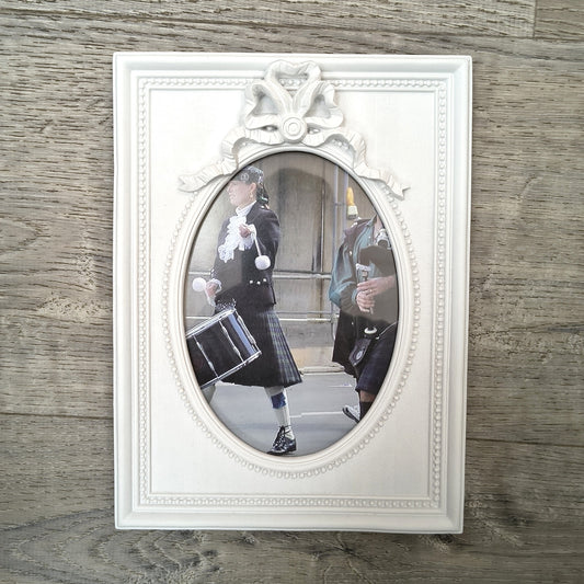 Vintage bagpiper and drummer parade photo in an ornate white oval frame