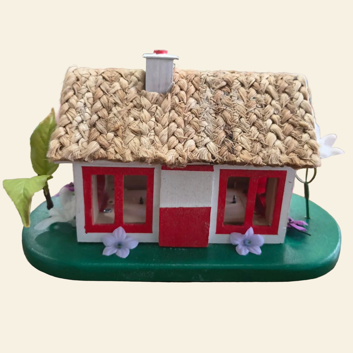 Miniature Irish thatched cottage with red windows and a straw-style roof