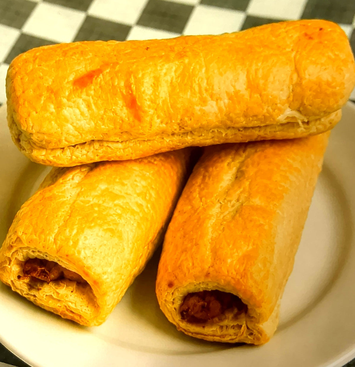 Large flaky sausage rolls on a plate